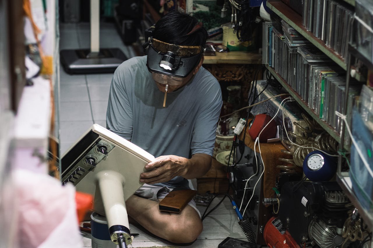 A Vietnamese technician works intently repairing a vintage radio in a cluttered workshop in Hanoi.
