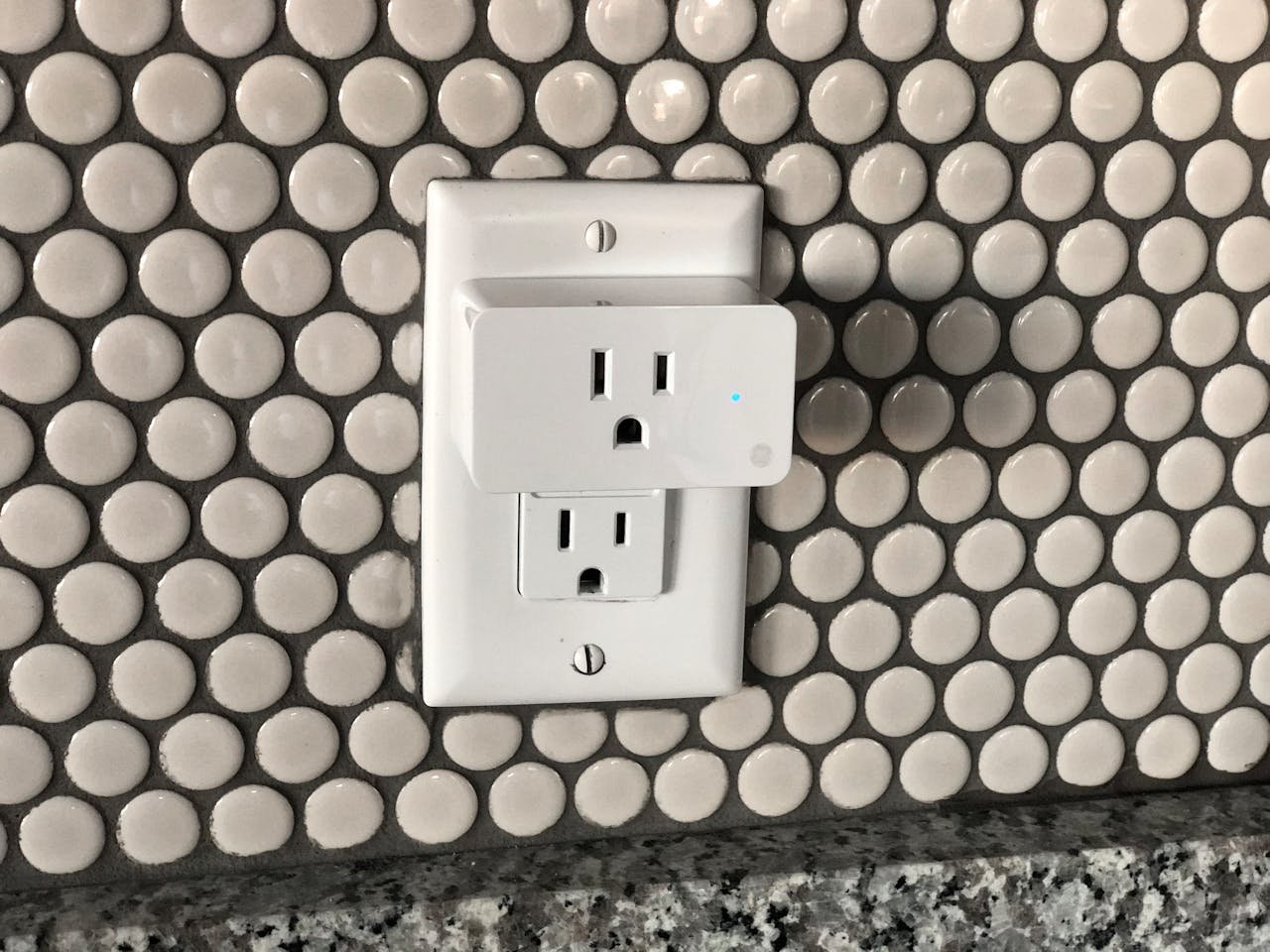 Close-up of a smart plug on a tiled wall showcasing contemporary interior design style.